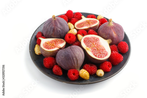 Fresh figs, strawberries and raspberries on blue ceramic plate isolated on white background. side view