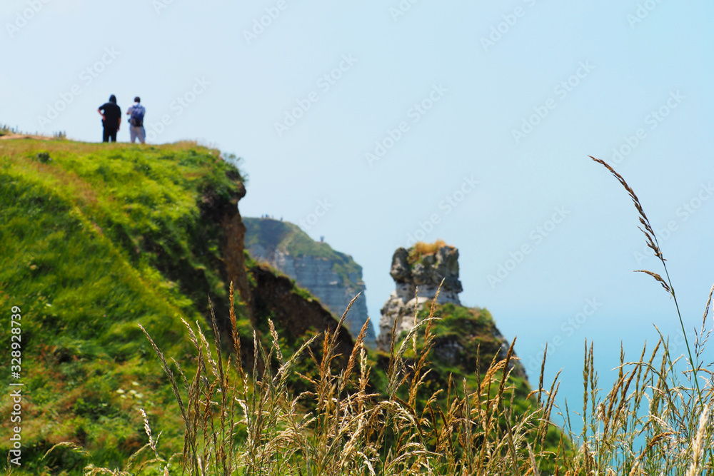 Tourists on the top of the cliffs of Etretat, France on a sunny summer day. Coast of the atlantic ocean