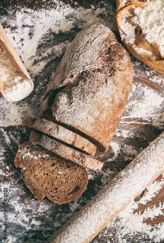 Bread loaf and slices covered with white flour, top view