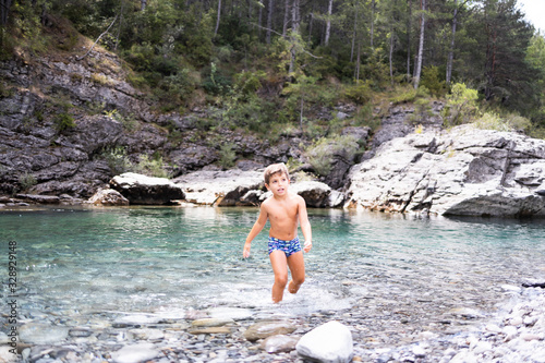 Little child in the middle of a wild river