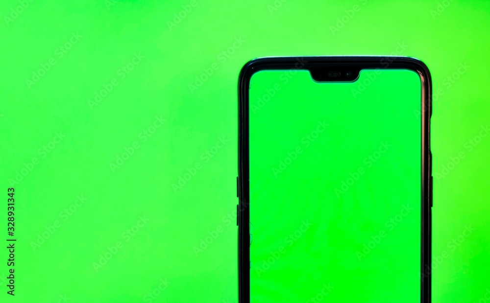 Man's hand shows mobile smartphone with green screen isolated on green background. Mock up mobile Man's hand shows mobile smartphone with green screen isolated on green background. Mock up mobile