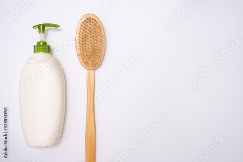 Anti-cellulite products for prevention and treatment of cellulite and for body massage  wooden brush  plastic bottle of body lotion on white background with copy space