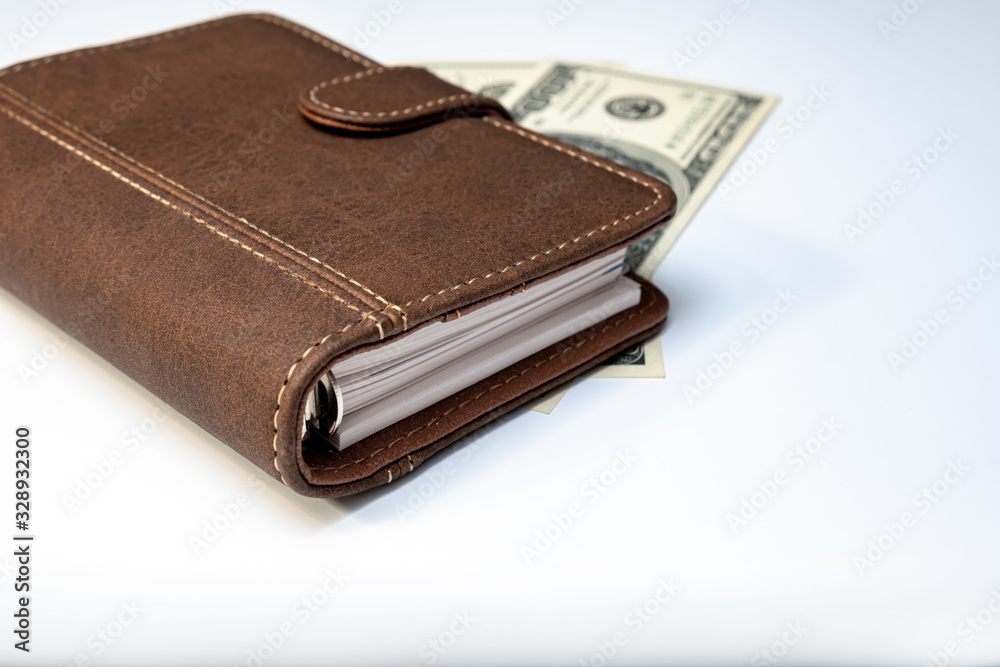Dollars, notebook and a pen on white background close up as a symbol of wealth and financial prosperity, earning money and richness Dollars, notebook and a pen on white background close up as a symbol of wealth and financial prosperity, earning money and richness