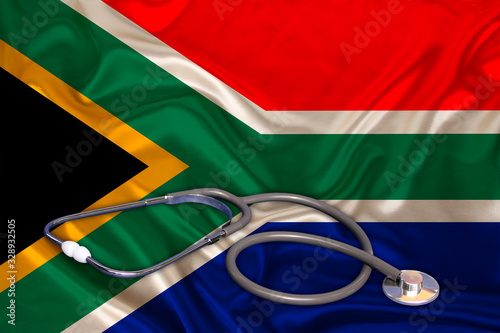 doctor’s tool, medical stethoscope, lies on the silk national flag of the state of South Africa, the concept of tourism, insurance, health, pediatrics
