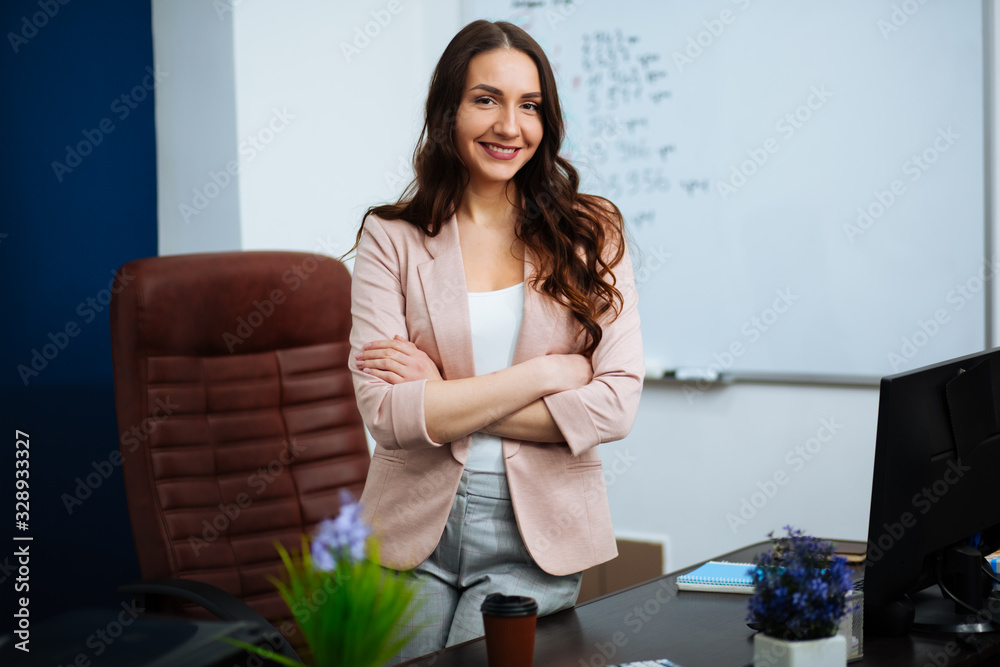 Stylish attractive young businesswoman with lovely smile standing in front of desk at office smiling at camera Stylish attractive young businesswoman with lovely smile standing in front of desk at office smiling at camera