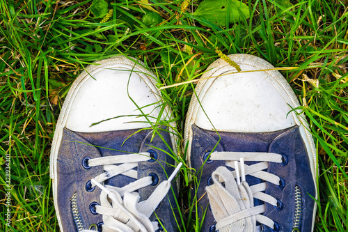 Old, dirty, shabby sneakers on the green grass. Hiking Travel Concept.