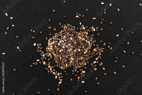 Pile of chia seeds on black background, top view