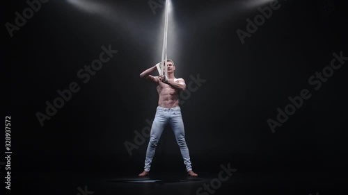 4k Muscular circus aerialist on the aerial straps in black studio photo