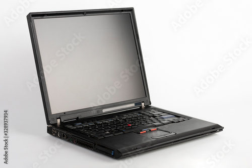 Old laptop on white background, which was produced in 2005, outer cover reinforced titanium, metal hinges, red trackpoint