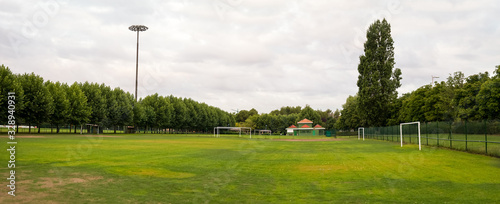 Panoramic view of sports facilities with football field for fans surrounded by trees and the changing rooms in the background in urban public park photo