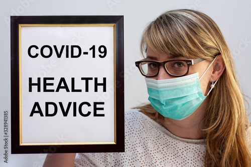 Beautiful european woman holding a frame with a COVID-19 related text Health Advice