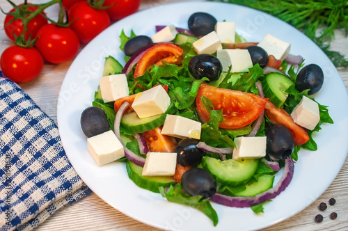 Greek salad with tomatoes, cucumbers and feta cheese with olives on the table