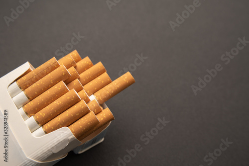 Cigarettes in pack. Yellow filter. Harm to health. Bad habit.