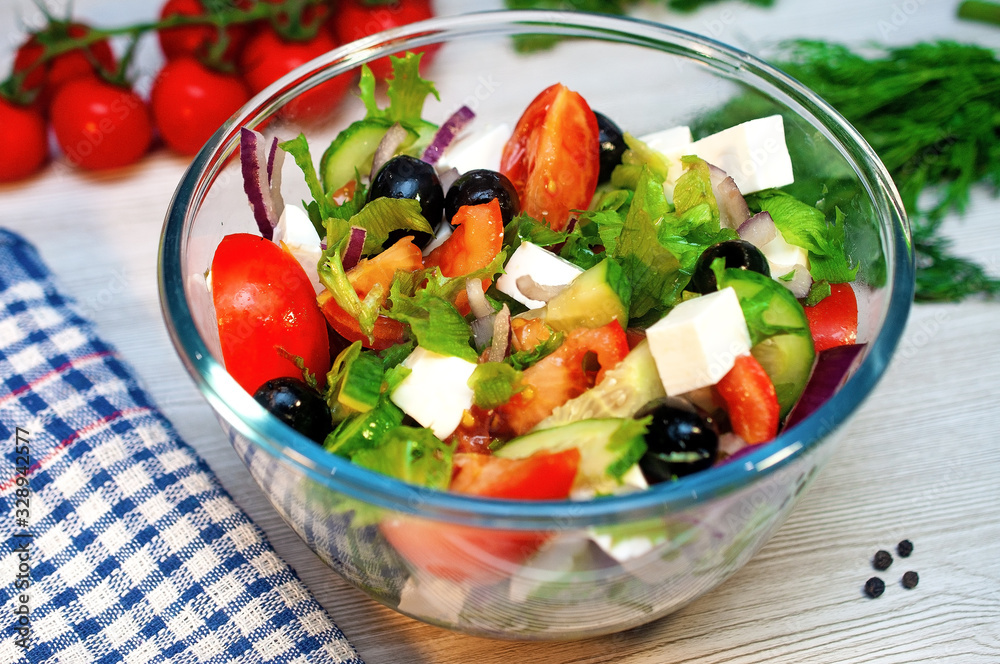 Greek salad with tomatoes, cucumbers and feta cheese with olives on the table