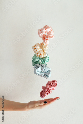 Lot of floating Colorful silk Scrunchies on womas hand isolated white. Hairdressing tools and accessories. Hair Scrunchies, Elastic HairBands, flying or falling Scrunchie Hairband for girl. copy space