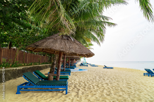 Long Beach  Phu Quoc Island  Vietnam. Nobody on the beach. Palm tree bamboo umbrellas and sun chairs in background.