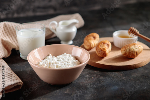 Cottage cheese with a glass of milk and croissants with honey on the table  space for text. Tasty breakfast.