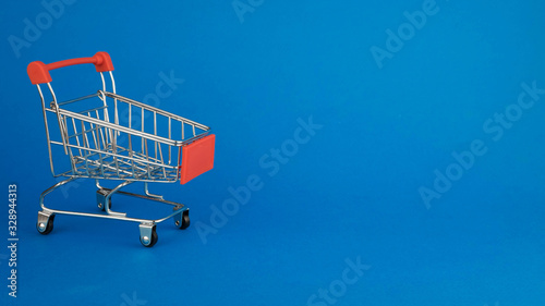red shopping cart standing on a blue background on the left side