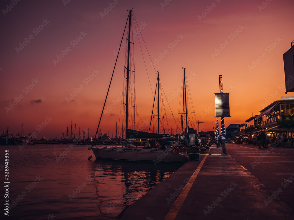 Limassol, Cyprus, promenade after sunset with yachts and boats in port, famous mediterranean city resort in twilight.