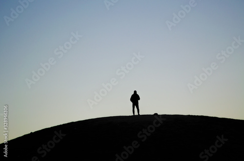 Silhouette of a person placed in the middle of a hill during a sunrise