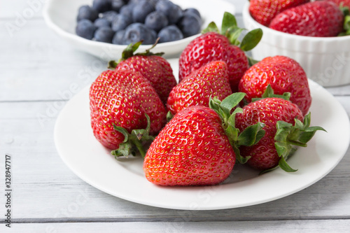 Fresh berries  strawberries and blueberries    in plates on the table.