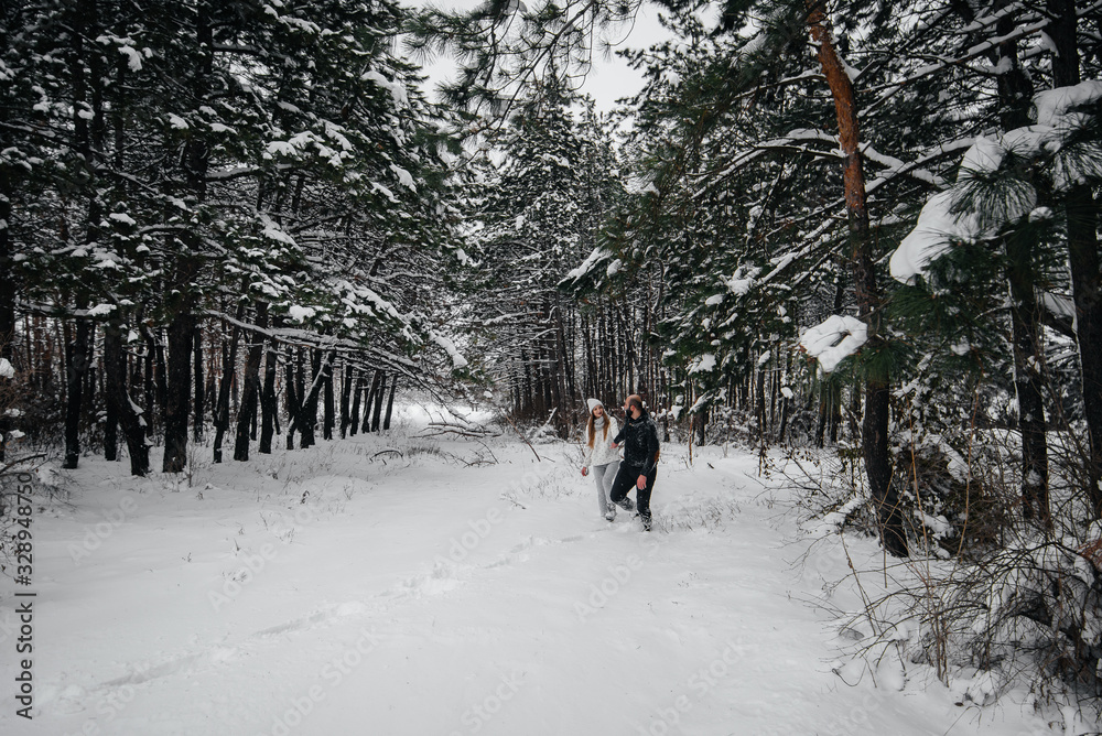 A couple embraces in a snowy forest against a background of trees