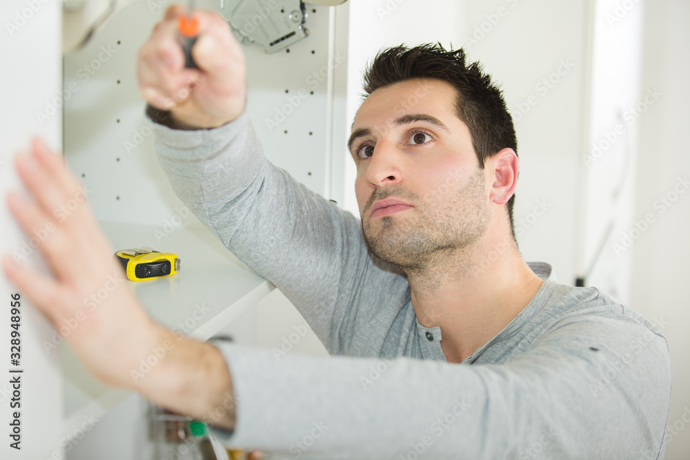 man working on a new kitchen installation man working on a new kitchen installation