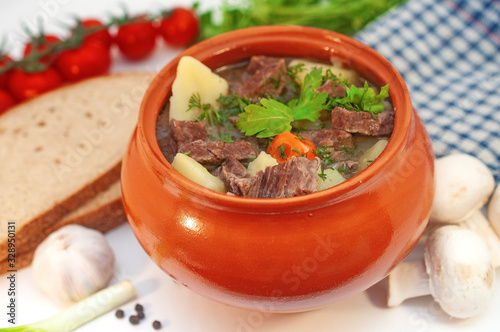 Roast in a pot with beef meat and potatoes on the table