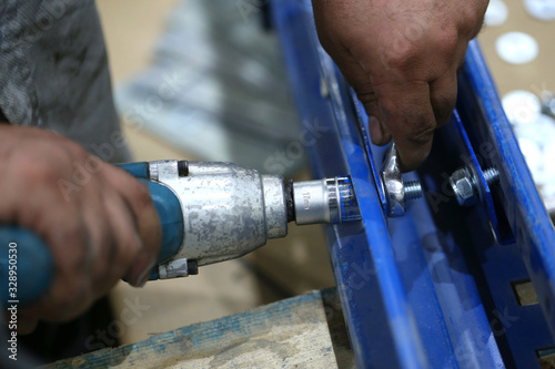 Картината върху платно One warehouse worker in with power tool tightening screw during rack arrangement