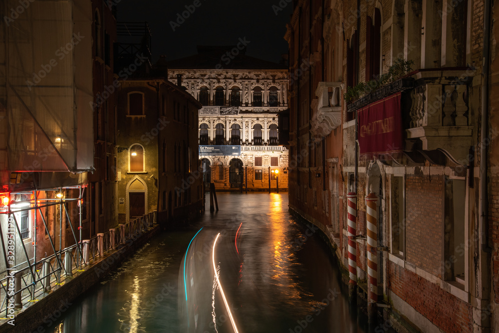 View  to the Ca Pesaro International Museum of Modern Art at Night, a Boat driving on the rio di San Falice, Venice/Italy