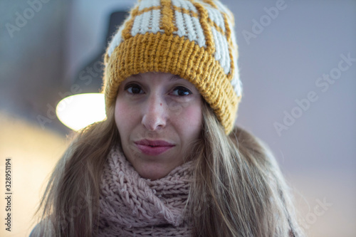 Close portrait of young woman with long hair in yellow hat with scarf