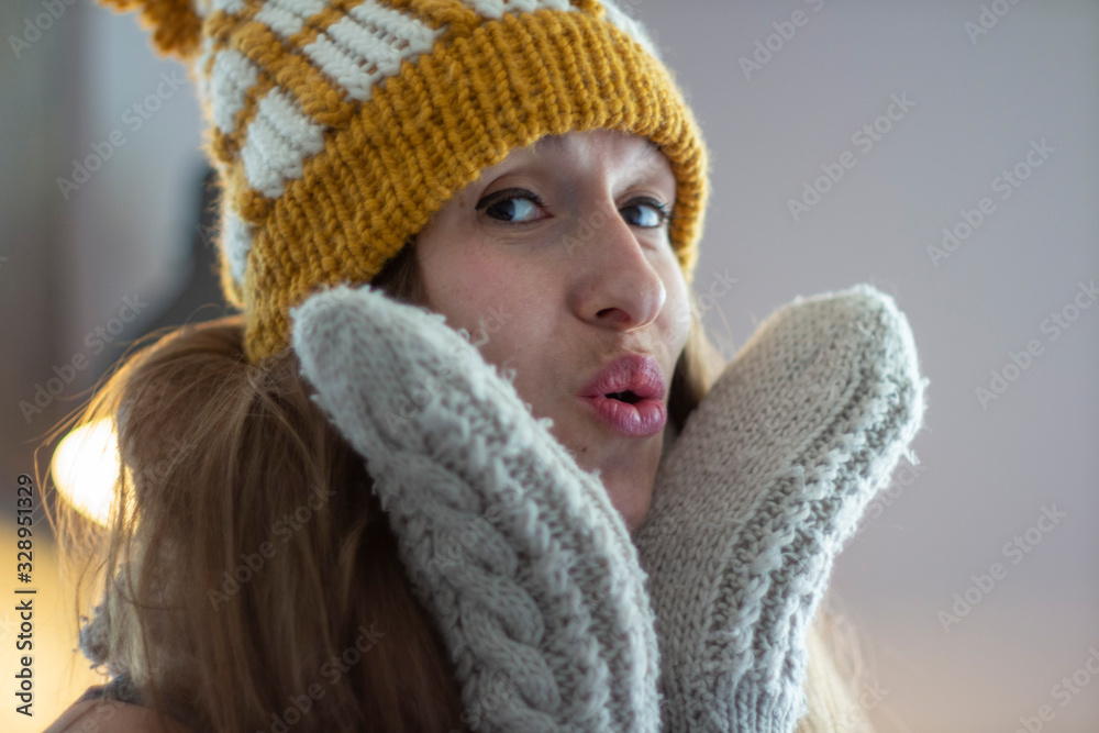 Close portrait of young woman with long hair in yellow hat with scarf and white gloves