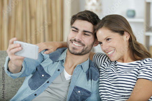 young happy couple taking selfie on sofa