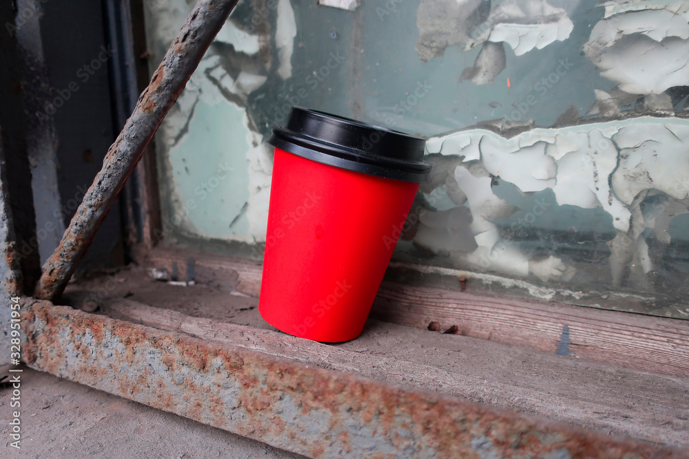 red cup with a lid for coffee forgotten on the windowsill of an old window red cup with a lid for coffee forgotten on the windowsill of an old window