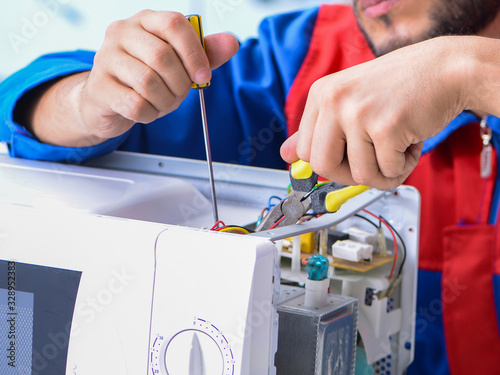 Young repairman fixing and repairing microwave oven