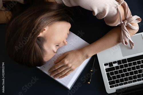 Принти на полотні Top above view head shot close up restless young woman freelancer sleeping on table, tired of hard work at home