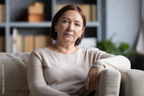 Fotografi Head shot portrait peaceful tranquil middle aged old woman resting on cozy sofa alone at home