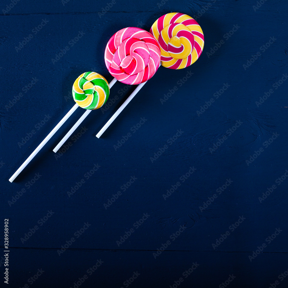 Top view of various bright colored lollipops on a black background. Children party concept. Top view of various bright colored lollipops on a black background. Children party concept.