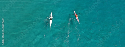 Aerial drone ultra wide photo of fit men competing in sport canoe in tropical exotic bay with emerald sea