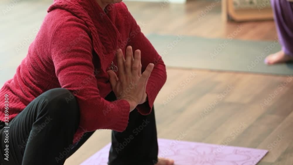 Static selective focus of woman with breast cancer on yoga mat practicing malasana with folded hands and block while doing exercise to heal cancer Static selective focus of woman with breast cancer on yoga mat practicing malasana with folded hands and block while doing exercise to heal cancer
