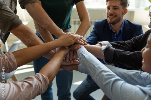 Close up of overjoyed diverse businesspeople stack hands engaged in teambuilding activity at briefing, excited multiracial colleagues motivated for shared business success in training at meeting