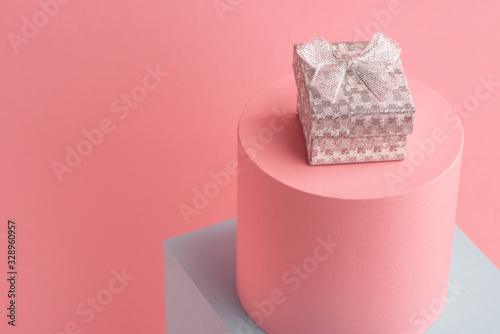 Little sparkling silver gift box on pink background with copy space
