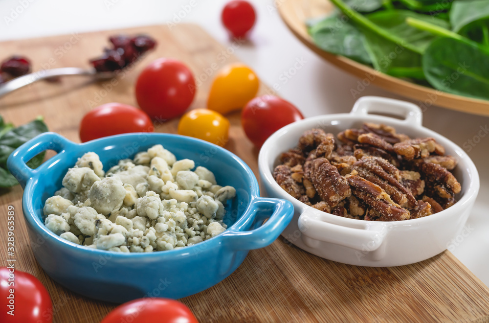 Salad ingredients close up. Spinach, tomatoes, blue cheese, pecans, cranberries on a kitchen table