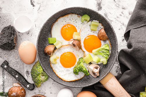 Foto Frying pan with cooked eggs and vegetables on white background