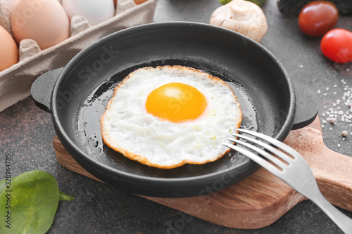 Frying pan with cooked egg on dark background