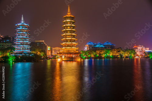 Guilin, China - May 9, 2010: Riyue Shuangta Cultural Park. Wide shot on the Twin Pagodas in Shanhu Lake, the silver and the gold, under pitch black night. Their lights reflected in water.  photo
