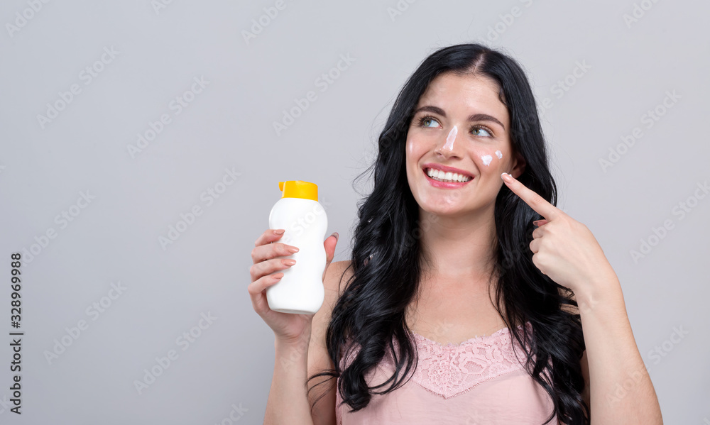 Young woman with sunscreen on a gray background Young woman with sunscreen on a gray background