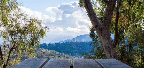 wooden picnic table overlooking lush forests and hillsides in the Los Angeles basin under blue skies