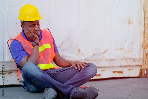 Technician man sit near the cargo container and act as sleepy and tired during working time. © narong