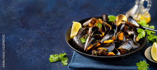 Close up of delicious steamed mussels in a plate on blue background